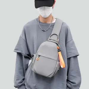 Men's large capacity grey crossbody chest bag with orange zipper detail on male model