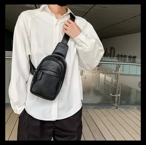 Detail der schwarzen Leder-Brusttasche mit Litschistruktur am Modell im urbanen Design