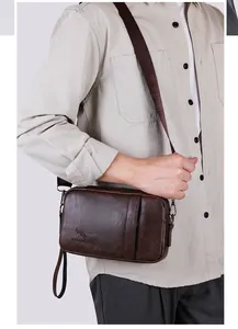 Detail view of dark brown textured leather crossbody bag with logo on a model