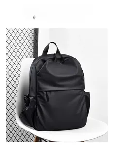 Minimalist black waterproof travel backpack shown on a white chair in a modern room