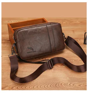 Close-up of brown PU leather bag with kangaroo logo engraving and nylon strap on wood