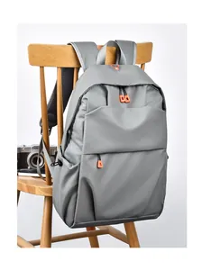 Detail of grey laptop backpack with orange zippers hanging on a wooden chair