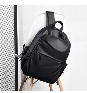 Minimalist black waterproof laptop backpack hanging on a white chair for urban commute
