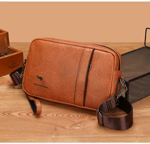 Detail of a brown textured synthetic leather messenger bag with adjustable shoulder strap