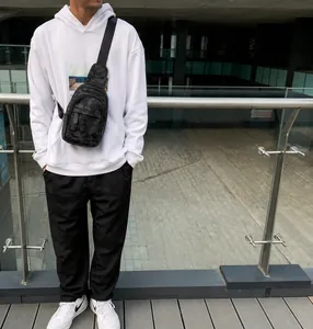Outdoor shot of a man wearing a black camo sports chest bag with waterproof fabric