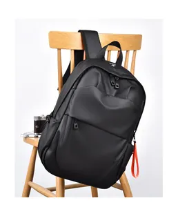 Detail of waterproof black laptop backpack on wooden chair with orange strap accent
