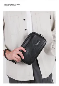 Detail shot of black leather grain bag with silver HCDS logo and wrist strap for men