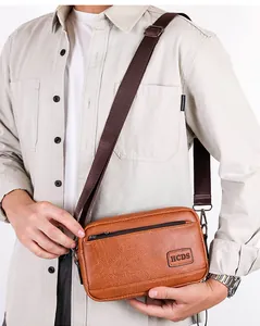 Detailed view of the brown vintage crossbody bag with HCDS logo and woven nylon strap
