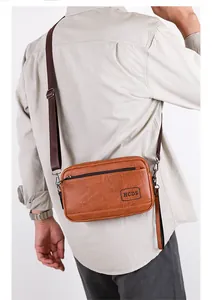 Detail of vintage brown textured leather crossbody bag with metal zippers and brand logo
