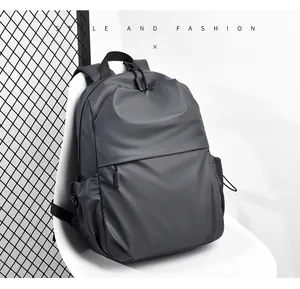 Minimalist dark gray travel backpack with dual zippers on a modern white chair