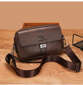Detail of a brown leather messenger bag featuring pebble texture and metallic hardware