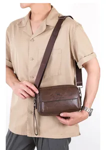 Detail of dark brown leather crossbody bag featuring adjustable strap and embossed logo