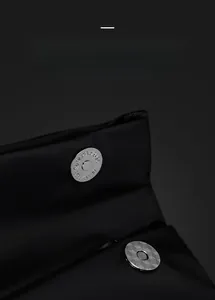 Macro shot of silver magnetic metal buckles on high-quality black nylon crossbody bag