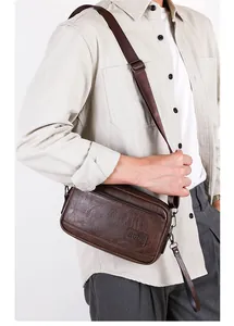 Close-up of vintage brown leather cross-body bag with embossed logo and metal zipper details