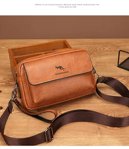Detailed view of brown textured leather men's crossbody bag with adjustable strap on wooden table