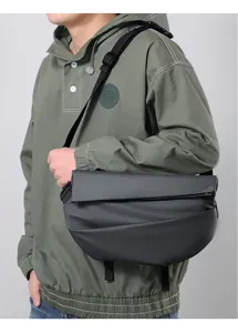Close-up of black waterproof crossbody bag with pleated texture on green hoodie