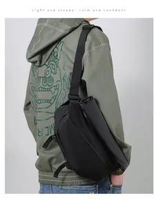 Detailed view of black waterproof crossbody bag featuring adjustable buckle on green hoodie