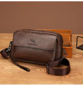 Detail of brown faux leather messenger bag with adjustable strap on a wooden surface