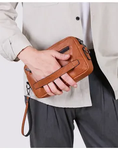 Nahaufnahme der braunen Herren-Clutch aus PU-Leder mit Lychee-Muster und Handschlaufe