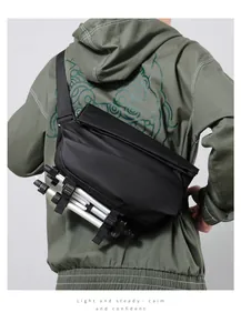 Detail showing the adjustable bottom straps holding a camera tripod on the black crossbody bag