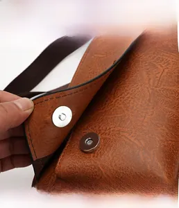 Detail of magnetic buckle and vintage brown leather texture on men cross body bag