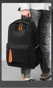 Close-up of matte black waterproof backpack featuring bright orange zipper pull accents
