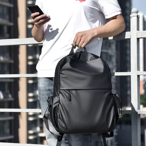 Minimalist black waterproof travel backpack shown on model in urban outdoor setting