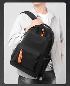 Modern black backpack with orange zipper straps being worn by a person on gray background