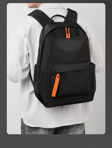 Rear view of model wearing a black nylon backpack with vibrant orange zipper accents