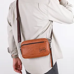 Brown leather men's multi-use crossbody bag with adjustable strap and HCDS logo
