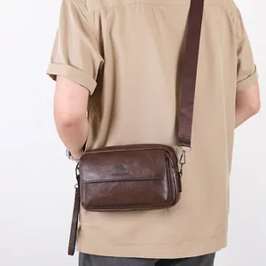 Men's dark brown leather crossbody bag with adjustable strap and kangaroo logo