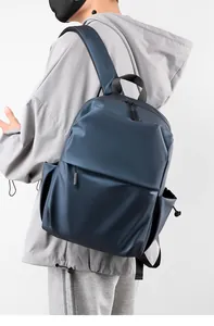 Navy blue minimalist laptop backpack featuring matte water-resistant fabric on model