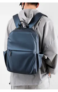Detail view of large minimalist dark blue laptop backpack shown on a male model's back