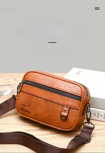Detailed view of brown lychee grain leather crossbody bag on a wooden table with glasses