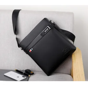 Detail of black pebbled leather briefcase featuring metal bar and tricolor ribbon tag