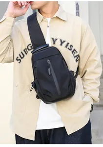Close-up of black waterproof travel chest bag on model showing front zipper and strap