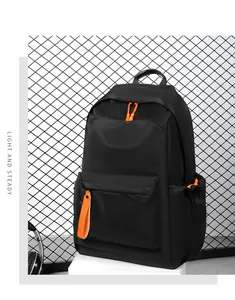 Detail of black nylon backpack with orange zipper accents next to headphones