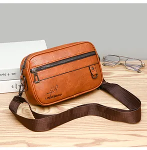 Close-up of brown vintage leather crossbody bag featuring textured fabric strap and metal loop