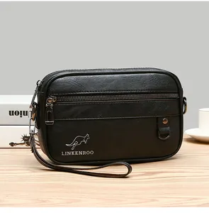 Detail of black pebbled leather crossbody bag with logo on a wooden desk with coffee