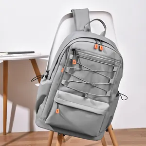 Grey college backpack with mesh pocket and orange zippers on a modern white chair