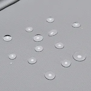 Waterproof grey fabric backpack with geometric texture showing water droplet resistance
