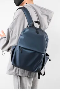 Side view of matte navy waterproof backpack with side drawstring pocket on male model