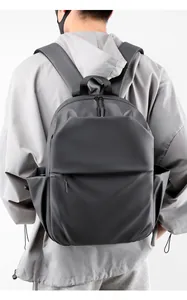 Rear view of a man wearing a minimalist matte black waterproof backpack for urban commuting