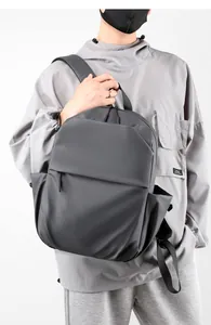 Man in gray hoodie wearing minimalist waterproof dark gray laptop backpack for daily use