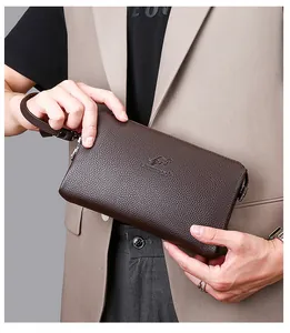 Details einer dunkelbraunen Leder-Herrentasche mit Logoprägung und praktischer Handschlaufe