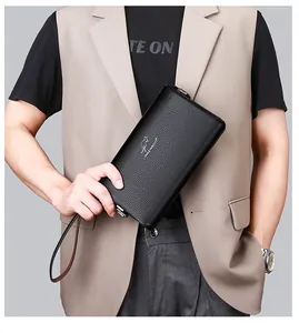 Nahaufnahme der schwarzen Leder-Clutch mit Lychee-Struktur und Markenlogo in der Hand