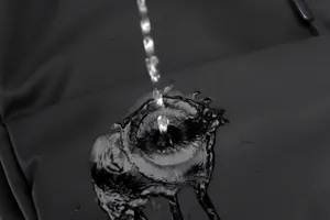 Gros plan du tissu imperméable montrant des gouttes d'eau sur le sac à dos noir