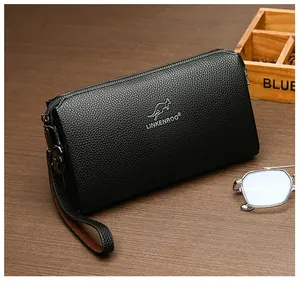 Detailansicht der schwarzen Herren-Lederclutch mit Logo auf elegantem Holzhintergrund