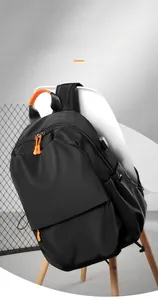 Detail of black backpack showing orange zipper pulls and built-in USB charging port