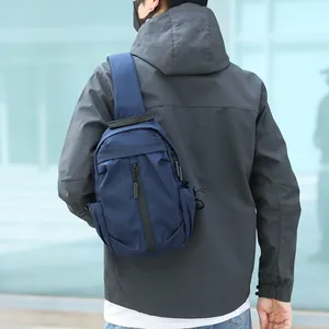 Zaino monospalla blu navy impermeabile con porta USB indossato da un uomo